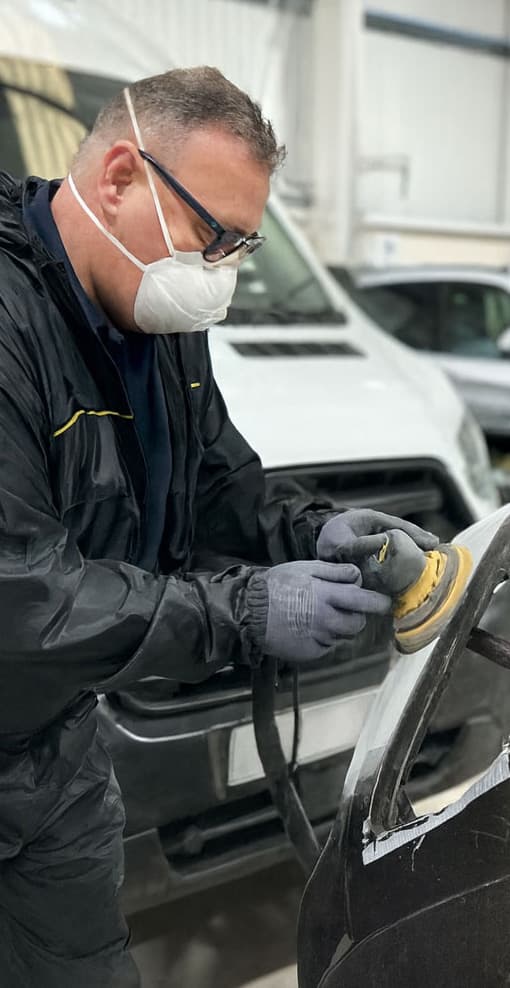 Bodyshop technician preparing a commercial vehicle panel for respray
